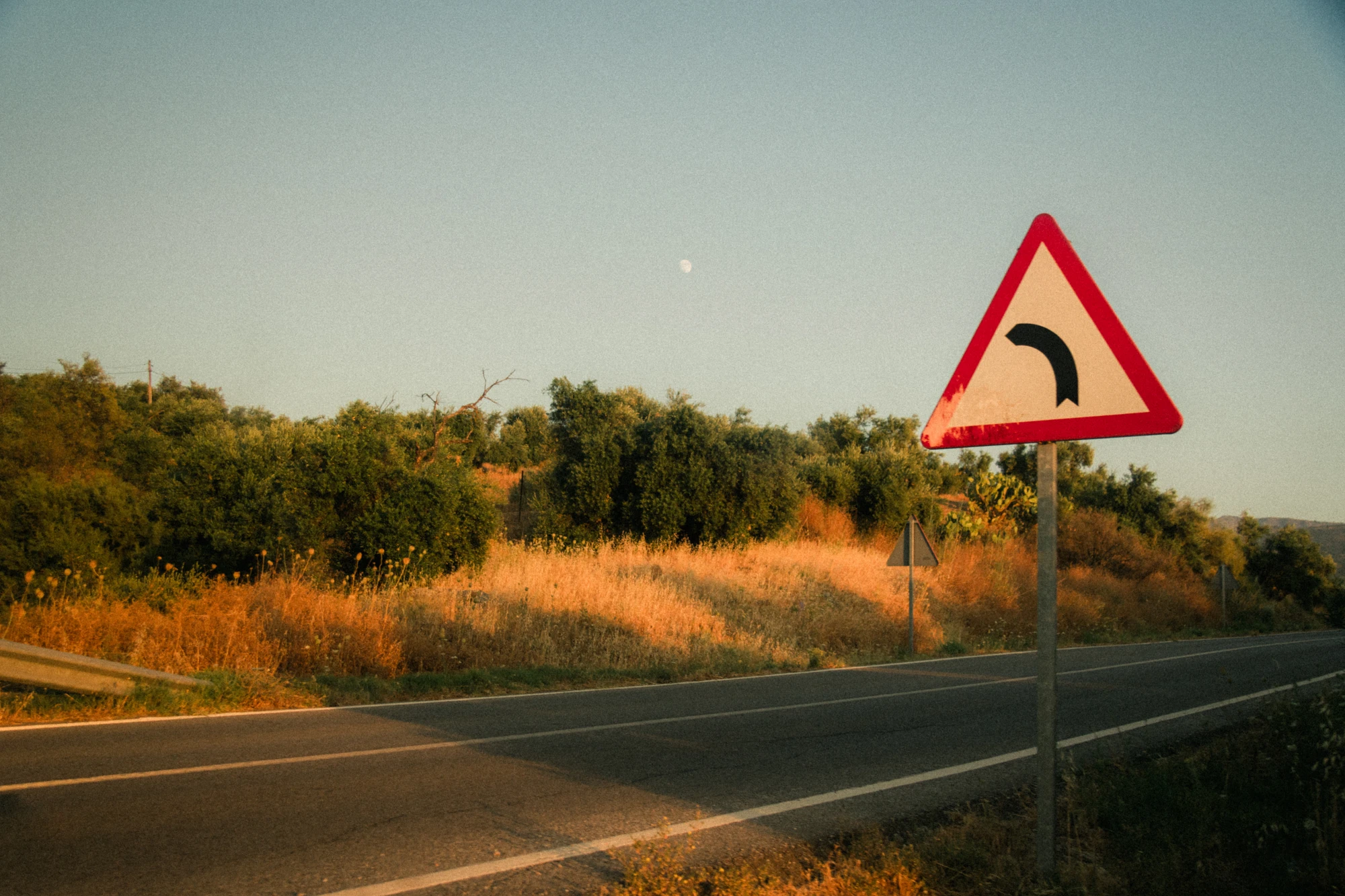 Road curve sign at golden hour in Spain